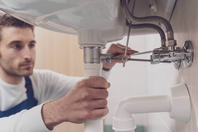 Victor, a plumber, fixing a sink in a bathroom.