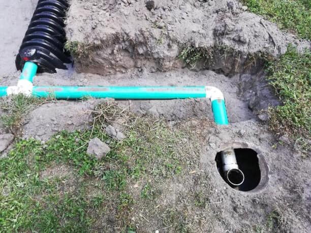 A green pipe with a green pipe in the ground, representing Victor Plumbing and their septic services.