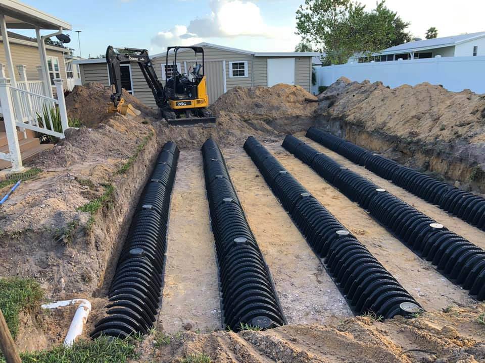 Victor Plumbing installing black pipes for a septic system in a yard.