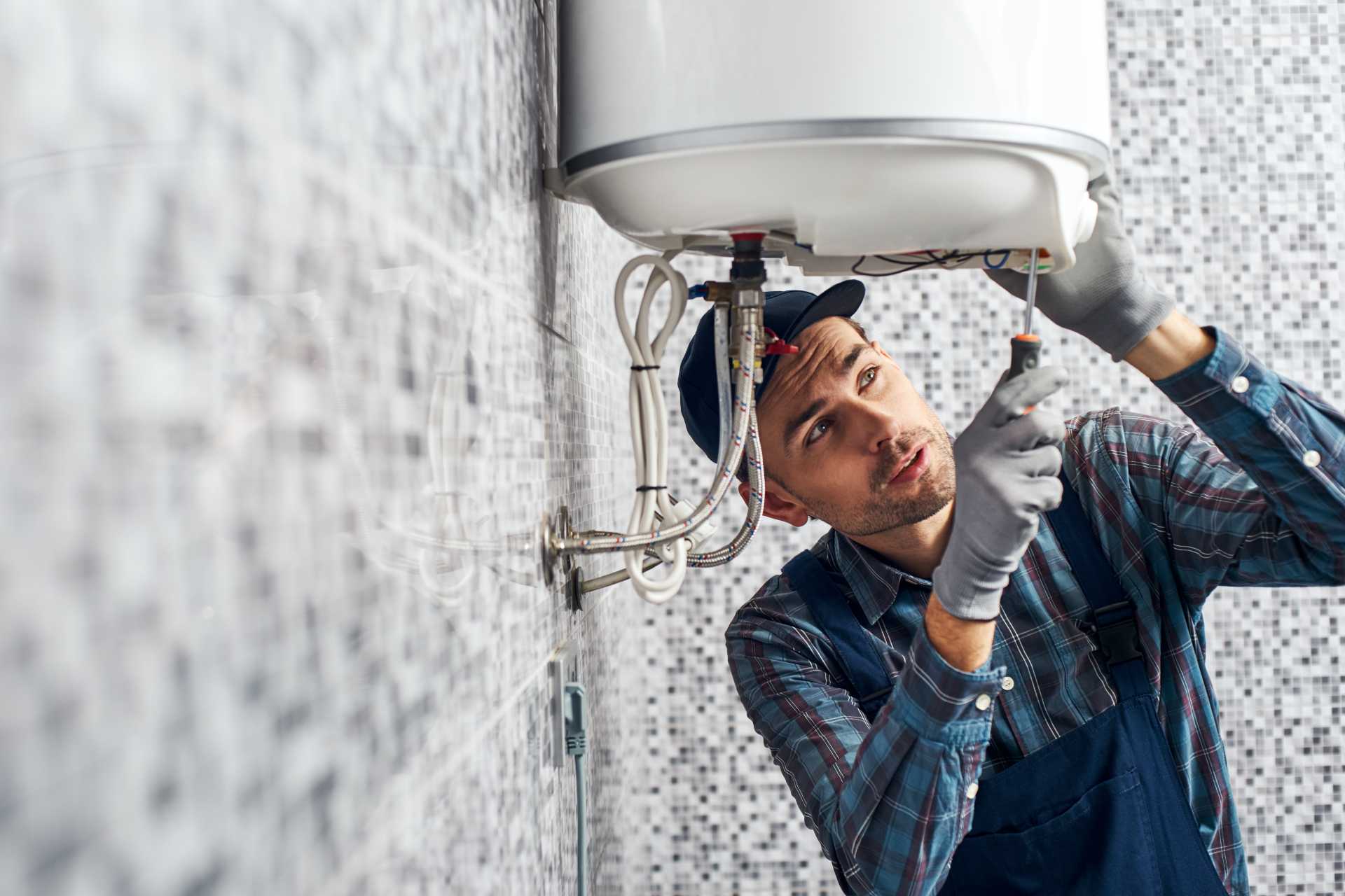 Victor, a plumber from Victor Plumbing, fixing a water heater in a bathroom.